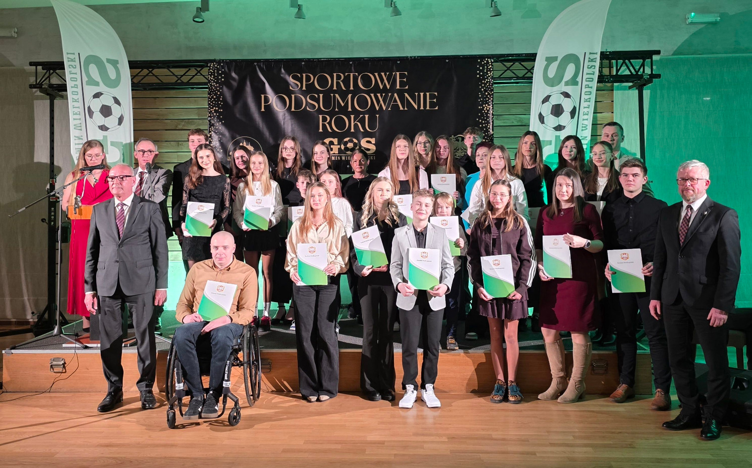 Grupa sportowców stoi na scenie.